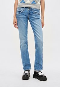 Svetlomodré riflové nohavice s priamym strihom, vybavené prednými vreckami a štandardným pásom so strieborným gombíkom.