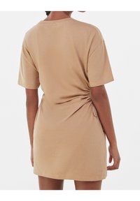 Krótkosleeve'owa, beżowa sukienka z dżerseju z marszczeniem po lewej stronie, o luźnym kroju i okrągłym dekolcie. Gładka tekstura.