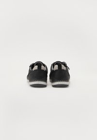 Pantofi sport negri cu accente gri. Material din nubuc și plasă, cu vârf rotunjit și cusături vizibile, având o căptușeală moale și o talpă texturată.