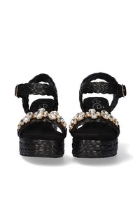 Sandalias de plataforma negras con tiras trenzadas, adornadas con una línea de cristales transparentes y herrajes dorados. Plantilla suave y texturizada.