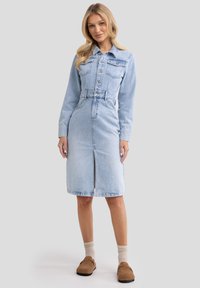 Denim haljina u svijetloplavoj boji ima kopčanje na gumbe sprijeda, duge rukave, dva džepa na prsima i prorez sprijeda. Ima strukturiran kroj s pojasom.