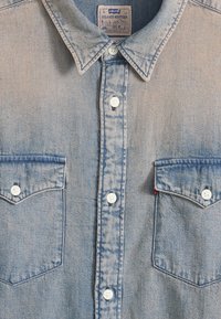Ανοιχτό γαλάζιο πουκάμισο από τζιν με κουμπιά, με δύο μπροστινές τσέπες με καπάκια και λευκά κουμπιά, με ετικέτα Levi's Relaxed Western, μέγεθος μεσαίο.
