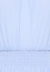 Tissu bleu clair avec des plis verticaux en haut et un froncé élastique en bas, créant un détail de ceinture texturée.
