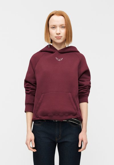 Μπορντό φούτερ με κορδόνι, μπροστινή τσέπη και μανίκια raglan. Διαθέτει μικρό μεταλλικό έμβλημα στο στήθος. Φοριέται με σκούρο τζιν.