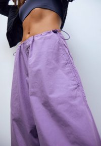 Pantalon ample lavande en tissu léger, doté d'une taille élastique avec cordon de serrage pour un ajustement optimal.