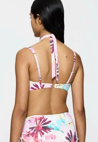 Biustonosz bikini w kwiatowy wzór w delikatnym różu z wielokolorowymi akcentami. Posiada regulowane ramiączka i zawiązywany na szyi fason, podkreślający zapięcie na plecach.