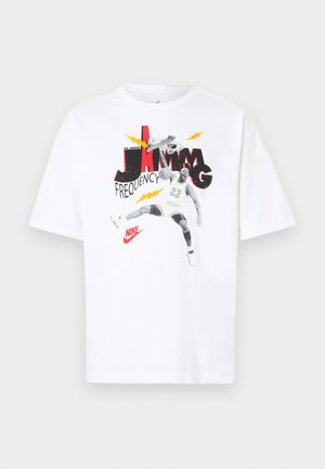 Tricou alb din bumbac cu un grafic ce reprezintă un jucător de baschet sărind pentru a face un dunk. Textul include "FRECVENȚA JAMMING" scris cu litere bold în roșu și negru.