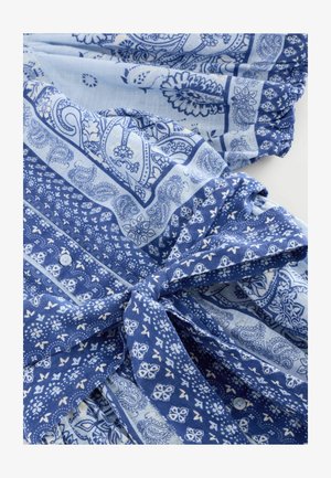 Niebieska tkanina w wzory prezentuje motywy paisley, wzory kwiatowe oraz kształty geometryczne. Ma związaną z przodu część i detale w postaci guzików, z miękką teksturą.