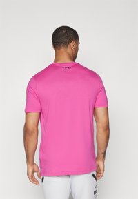 Rosa kortermet t-skjorte med rund hals og en liten svart logo bak. Stoffet ser glatt og lett ut.