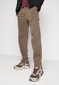 Bruna denimjeans med rak ben, med sidofickor och en strukturerad yta. Sammanfogat med mångfärgade sportskor.