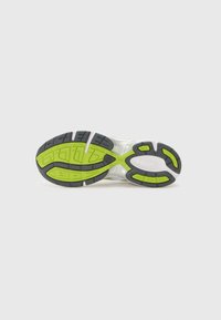 Sapatos de desporto brancos com solas de borracha pretas e verde-brilhante, apresentando padrões de piso e detalhes texturizados para aderência e suporte.