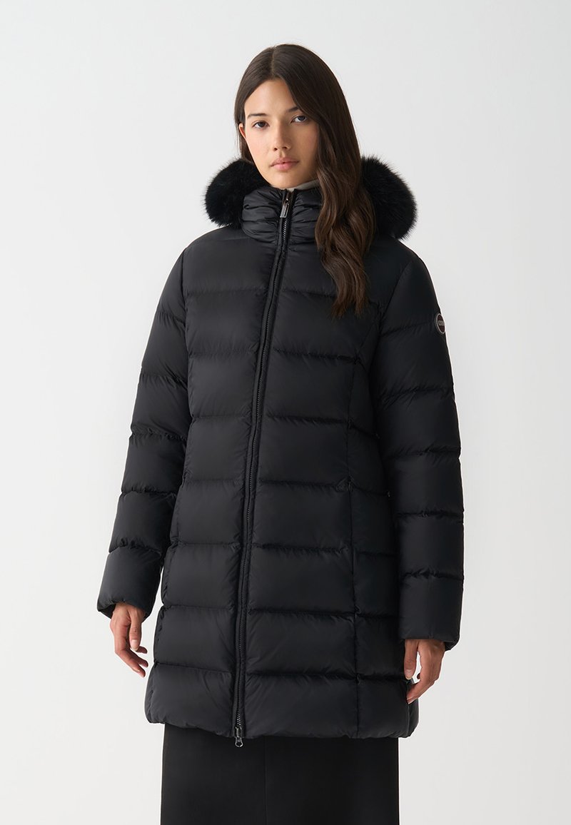 Giacca a collo alto nera imbottita con design a righe orizzontali, con bordo in pelliccia sintetica removibile. Presenta una chiusura frontale con zip e tasche laterali.