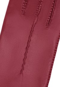 Gant en cuir rouge montrant une texture granuleuse, avec une surface lisse et des coutures décoratives le long de la longueur. Aucun matériel visible ni accents.