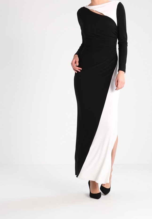 Lång klänning med svart och vit färgblockdesign, med en diagonal sprund och långa ärmar. Slät tyg med en sidoflik.