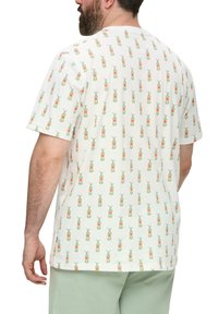 Korte mouwen katoenen t-shirt in het wit met een herhaald patroon van groene en rode ananas motieven. Relaxte pasvorm, zachte textuur en ronde halslijn.