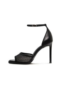 Sandale à talons hauts noire avec une bride, présentant un dessus en maille orné de petits strass et une finition lisse et brillante.