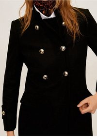 Sort dobbeltbrystet frakke med guldtonede knapper, struktureret pasform, tekstureret stof og sidelommer. Stylet med et mønstret tørklæde.