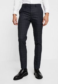 Donkerblauwe geruite tailortrousers met een slim fit, gemaakt van gestructureerde stof. Beschikt over riemlussen en zijzakken. Gecombineerd met zwarte nette schoenen.