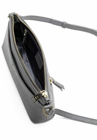 Borsa a tracolla in pelle grigia con finitura testurizzata, hardware dorato, chiusura con zip e una sola tracolla regolabile. L'interno presenta una fodera scura.