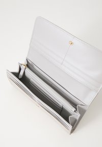 Portafoglio in pelle grigia con chiusura a scatto. Presenta più scomparti per carte, un compartimento con zip e una fodera interna liscia.