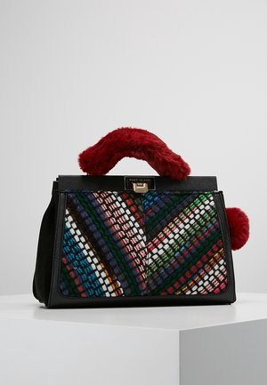 Sac à main noir avec un panneau avant tissé multicolore, une anse rouge duveteuse et un fermoir doré portant l'inscription « River Island » sur une surface blanche.