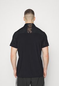 Black polo shirt with short sleeves, featuring a textured back panel and an orange geometric pattern along the neckline and upper back.