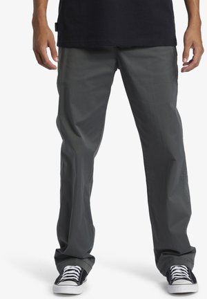 Gray lightweight pants with a straight fit, featuring side pockets and a smooth texture, paired with black and white low-top sneakers.