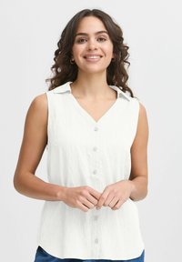 Biela bezramenná blúzka s predným zapínaním na gombíky, výstrihom do V a jemnou rebrovanou textúrou. Má golier a uvoľnený strih.