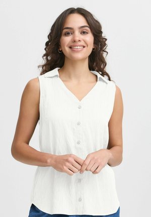 Blouse blanche sans manches avec un devant à boutons, un col en V et une texture à côtes subtile. Présente un col et une coupe décontractée.