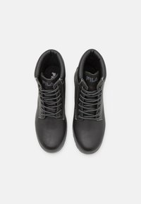 Botines de cuero negro con cordones grises, cuello acolchado y logotipo en la lengüeta. Suela de goma plana con superficie texturizada para un mejor agarre.