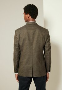 Blazer marrón de espiga con solapa de muesca, abertura simple y dos botones en las mangas, hecho de tejido texturizado.