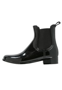 Bottine en cuir verni noir avec des panneaux latéraux en élastique. Présente un bout arrondi et un petit talon carré. Texture lisse, design épuré, avec une languette à l'arrière.