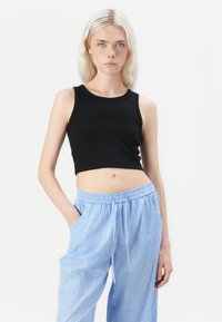 Zwarte cropped tanktop met een ronde hals, gecombineerd met blauwe gestreepte pantalon met kleine gouden accenten en een elastische tailleband.