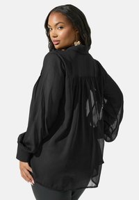 Blusa nera trasparente a maniche lunghe con colletto, design con pieghe sul retro e maniche arricciate, caratterizzata da una vestibilità ampia e una texture morbida.