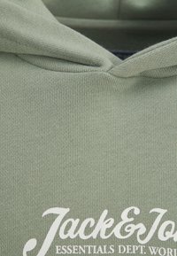 Lys grøn hoodie med ribbet tekstur og snoretræk i hætten. Fronten viser hvidt brandtekst.
