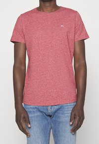 Červené melírované tričko s kulatým výstřihem a krátkými rukávy, s malým logem na levé straně hrudi. Vyrobeno z měkké bavlněné směsi.