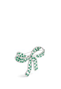 Broche en forme de nœud argenté orné de pierres vertes, avec une texture lisse et une finition polie, mettant en valeur un détail élaboré.