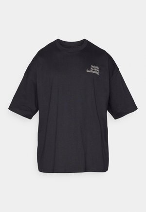 Črna oversize bombažna majica kratkih rokavov s okroglim ovratnikom. Ima belo besedilo: "Brez dodatkov, brez oglaševanja, začni teči."