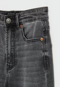 Högmidjade skinny jeans i mörkgrå denim, med kopparnitar, en framficka och subtila blekningar längs ytan.