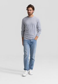 Grijze trui met lange mouwen, gecombineerd met blauwe jeans en witte sneakers. Casual outfit met een eenvoudig ontwerp en een zachte textuur.