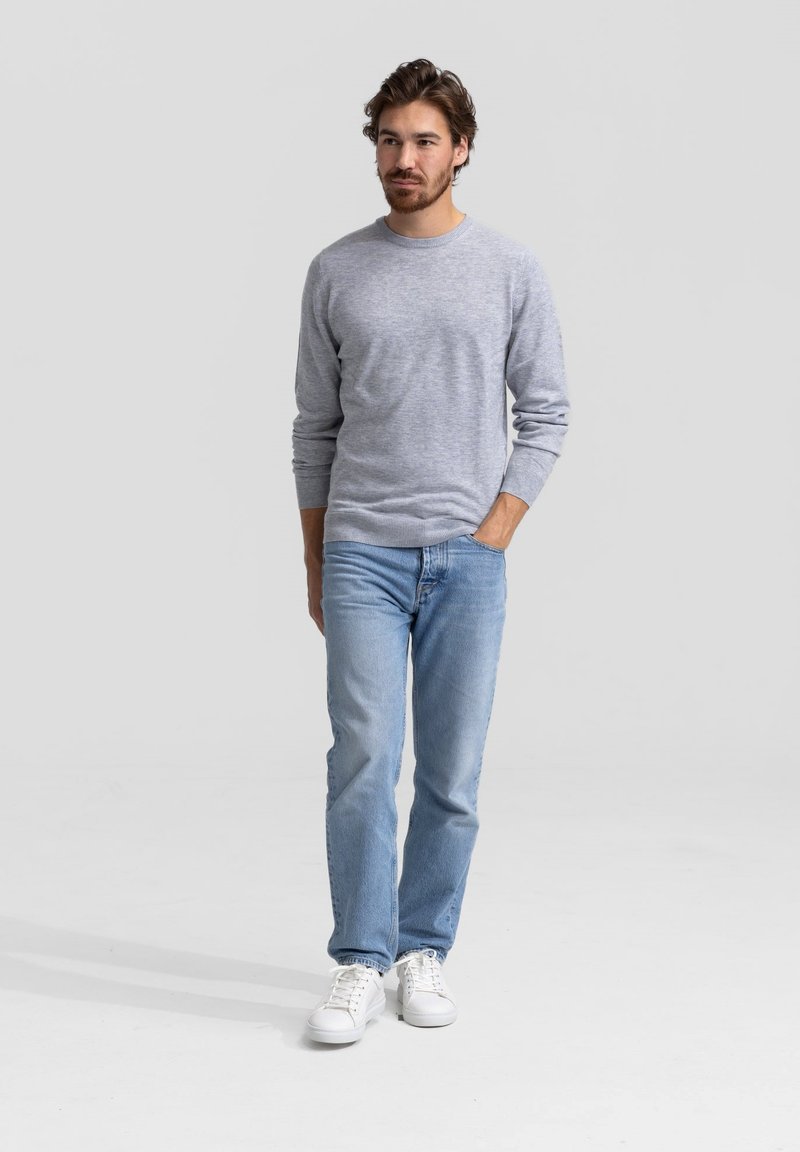 Grijze trui met lange mouwen, gecombineerd met blauwe jeans en witte sneakers. Casual outfit met een eenvoudig ontwerp en een zachte textuur.