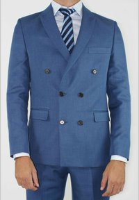 Costume bleu croisé en tissu lisse, avec des boutons noirs, deux poches frontales et un col cranté, assorti d'une cravate rayée.