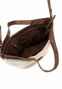 Bruine leren handtas met een zachte crèmekleurige fleece binnenkant, voorzien van een binnenzak met rits en een schouderband voor gemakkelijke draagbaarheid.