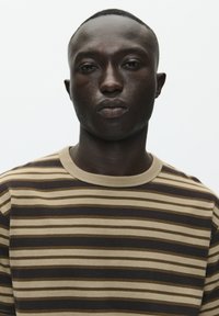 Stribet t-shirt i brune og beige nuancer med rund hals. Fremstillet af blødt stof, med horisontale striber i varierende bredder.