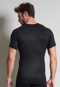 Black short-sleeve athletic shirt with a fitted design, made of smooth fabric. Features a crew neckline and raglan sleeves.