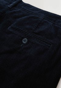 Navy corduroy pants featuring a back pocket with a button, ribbed texture, and a straight cut, highlighting vertical lines in the fabric.