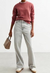 Ljusrosa stickad tröja med rund halsringning, kombinerad med högmidjade, löst sittande ljusgrå jeans och en beige handväska. Avslappnat skovalt ingår.