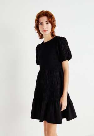 Svart klänning med en texturerad smockad byst och puffärmar, med en utsvängd kjol och rund halsringning. Slätt tyg, enkel design.