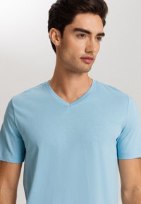 Light blue cotton t-shirt with short sleeves and a V-neck. Smooth texture, fitted design, minimal seams, and no visible patterns.