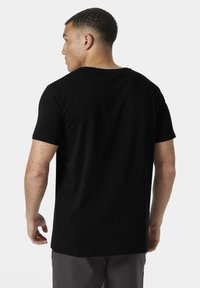 Camiseta de algodón negra con mangas cortas, cuello redondo, corte relajado y textura suave. Diseño limpio sin logotipos o patrones visibles.